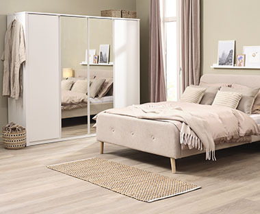 Kleiderschrank mit Spiegel und ein großes Doppelbett in einem modernen Schlafzimmer