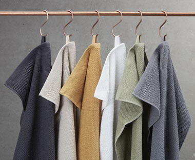 Handtücher in verschiedenen Farben auf einer Stange hängend