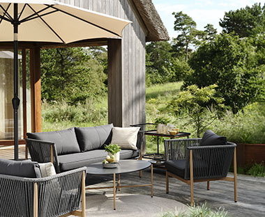 Stylisches Loungeset auf einer Terrasse unter einem Sonnenschirm