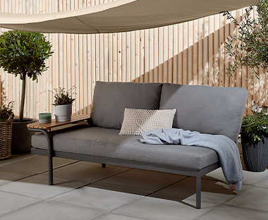 Lounge-Sofa unter einem Sonnensegel auf einer Terrasse 