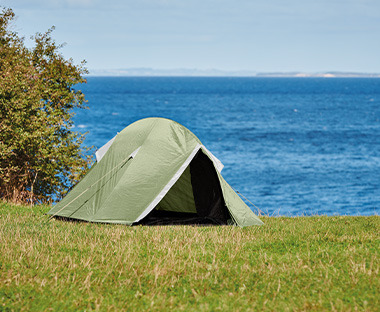 Zelt auf einer Wiese vor einem See