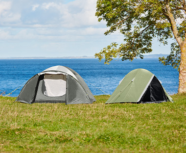 Zelte auf einer Wiese vor einem See
