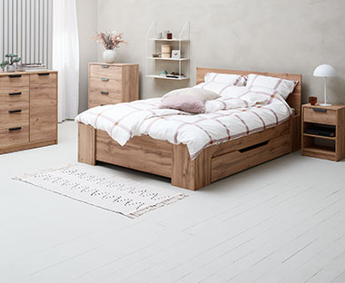 Bettgestell und Nachttisch sowie Kommoden aus Holz in einem Schlafzimmer