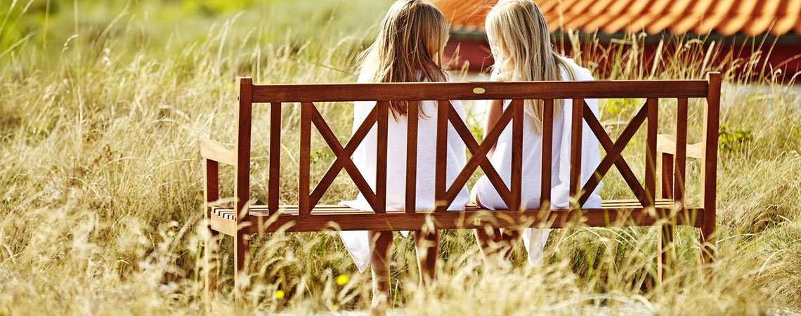 Zwei Mädchen sitzen auf einer Holzbank