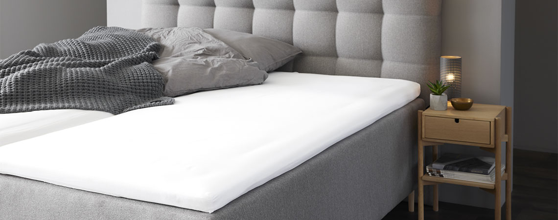 Schlafzimmer mit grauem Kingsize-Bett mit Topper und grauem Kopfkissen und Bettdecke