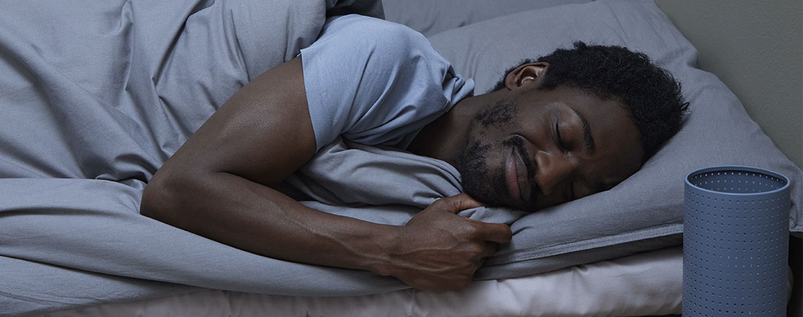Ein Mann schläft im Bett mit einer grauen Bettwäsche