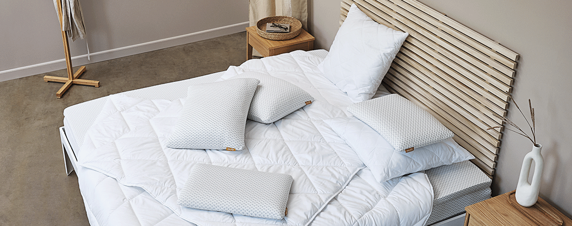 Schlafzimmer mit Bett, Matratze, Topper, Bettdecken und Kopfkissen im skandinavischen Design 