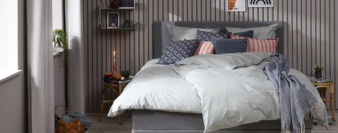 Stylisches Schlafzimmer mit einem grauen Bett und schöner Bettwäsche