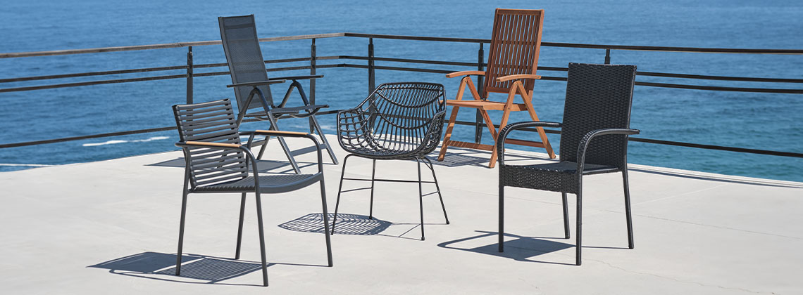 5 verschiedene Gartenstühle auf einer Terrasse mit Blick auf das Meer