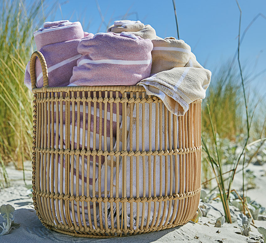 Großer Aufbewahrungskorb mit Strandtüchern darin an einem Strand