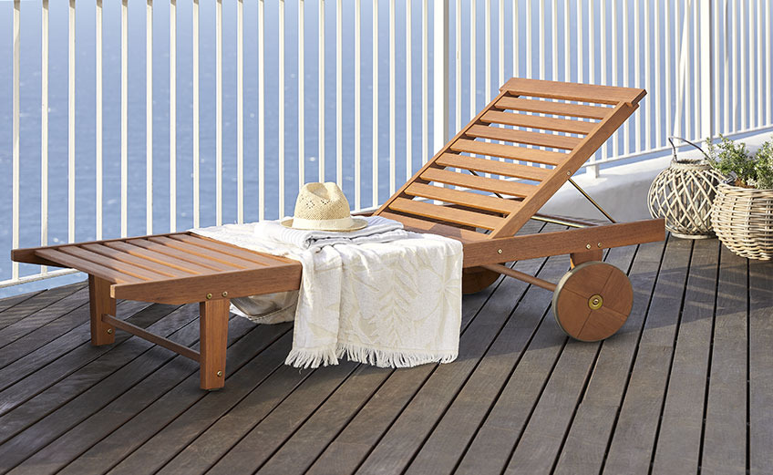 Sonnenliege aus Holz mit Rädern auf einem Balkon am Meer