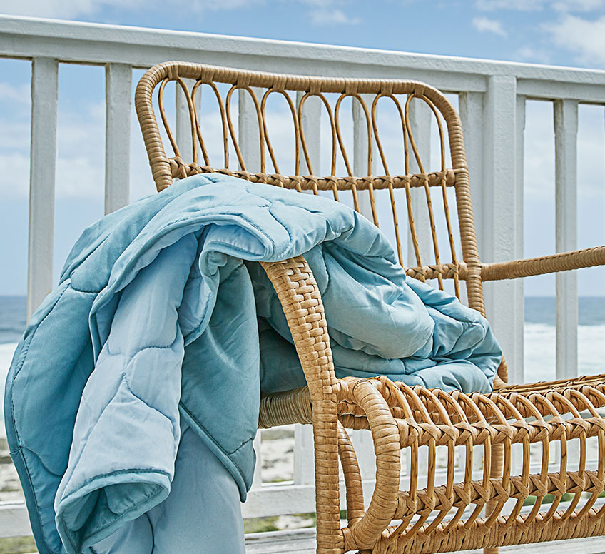 Sessel aus Rattan und eine blaue Sommerdecke auf einer Terrasse