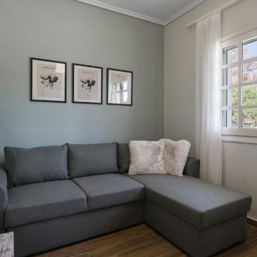 Schlafsofa MARSLEV mit Chaiselongue und OSCAR Bilderrahmen Möbliertes Wohnzimmer mit Sofa, Kissen und Dekoration
