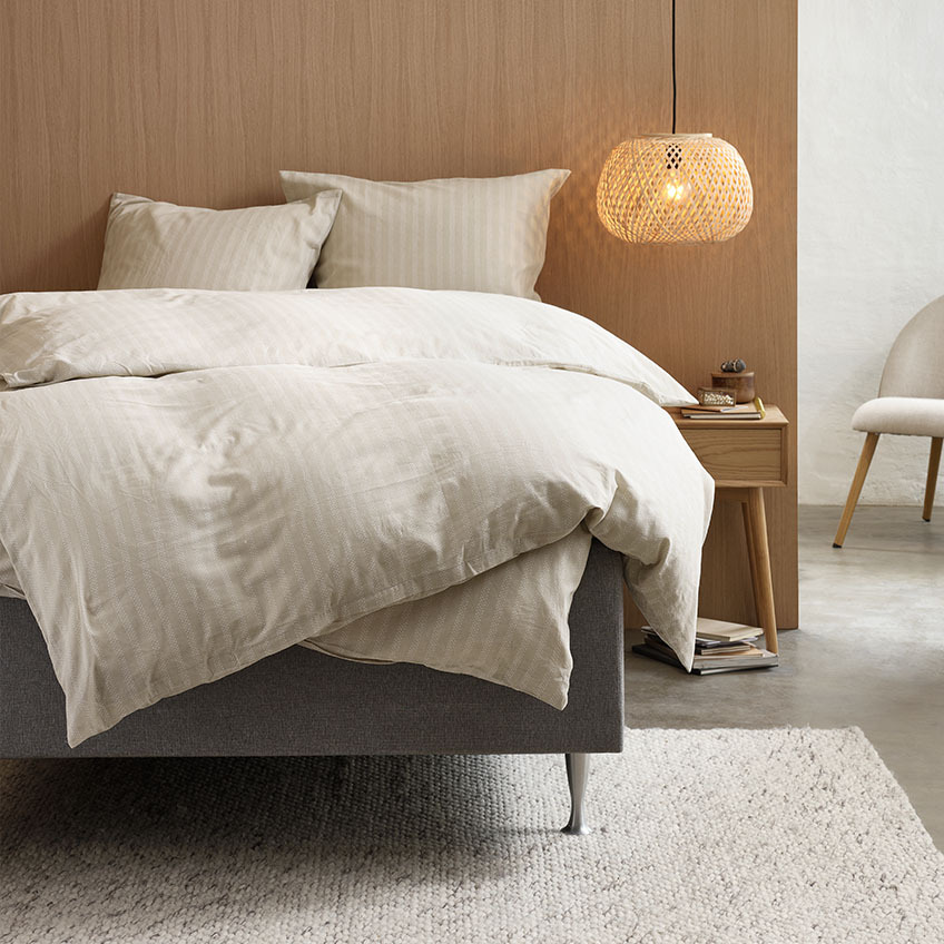 Bettwäsche aus Baumwollflanell in warmen Beigetönen mit Streifenmuster auf einem Bett im Schlafzimmer