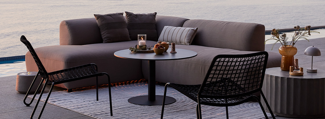 Allwetter-Loungesofa und Loungesesseln auf einer Terrasse bei Sonnenuntergang