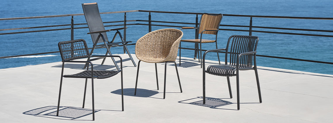 Eine Auswahl von fünf Gartenstühlen auf einer Terrasse am Meer