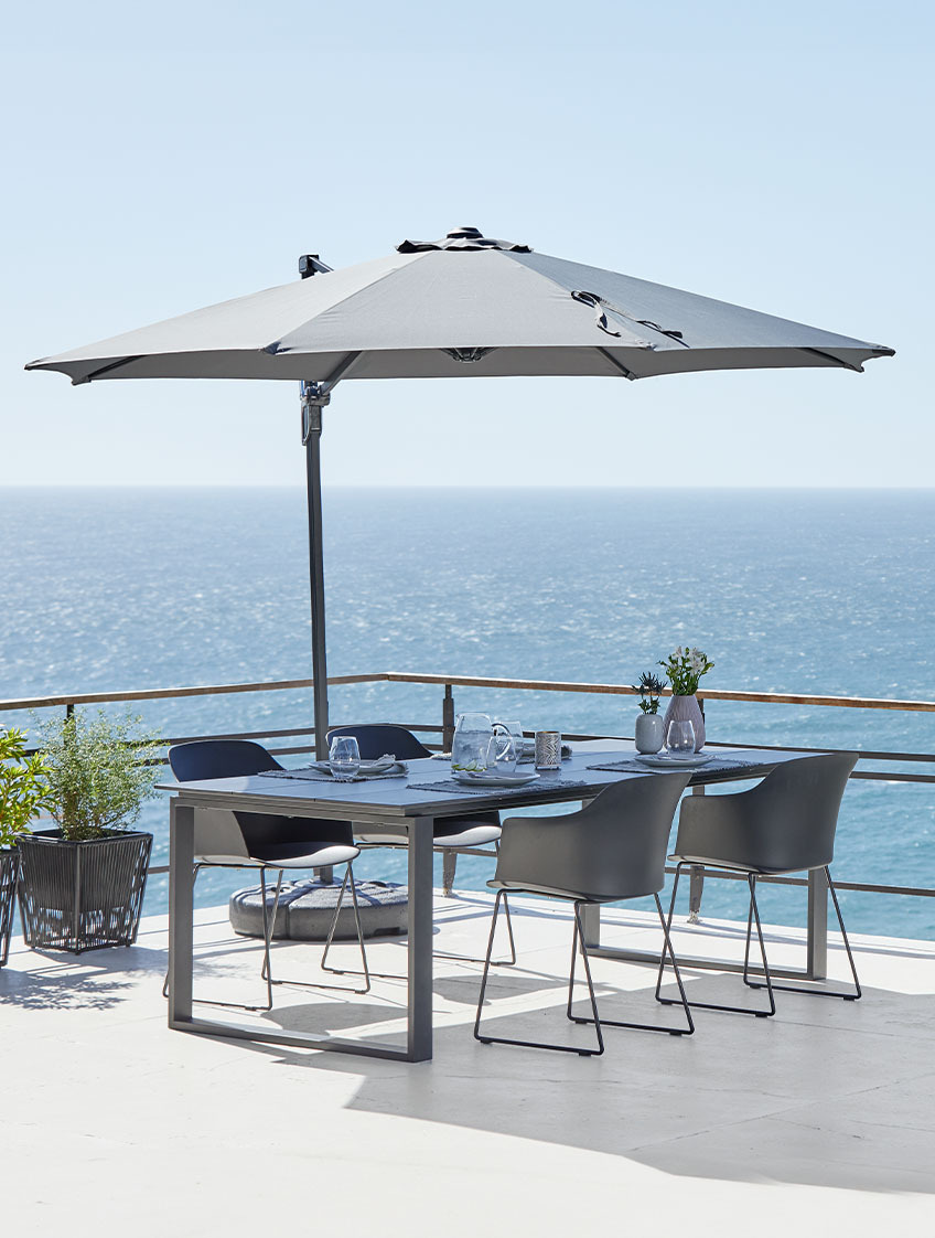 Großer Ampelschirm, Gartentisch und Stühle auf der Terrasse am Meer