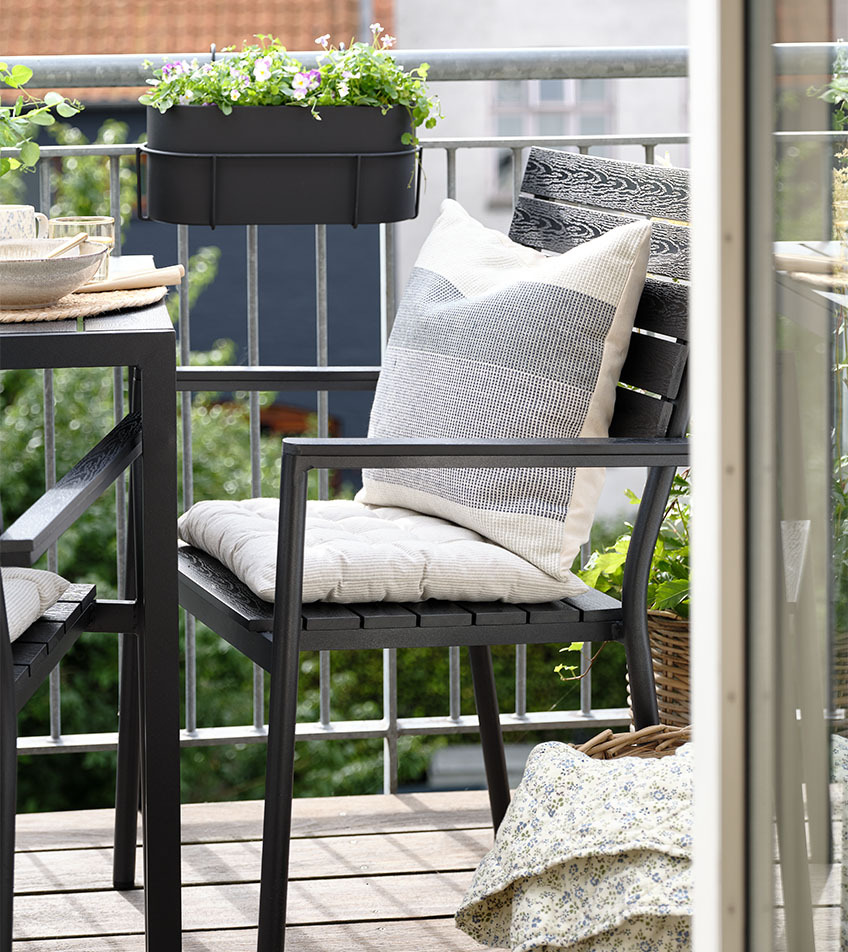 Schwarzer stapelbarer Gartenstuhl mit Sitzkissen auf dem Balkon