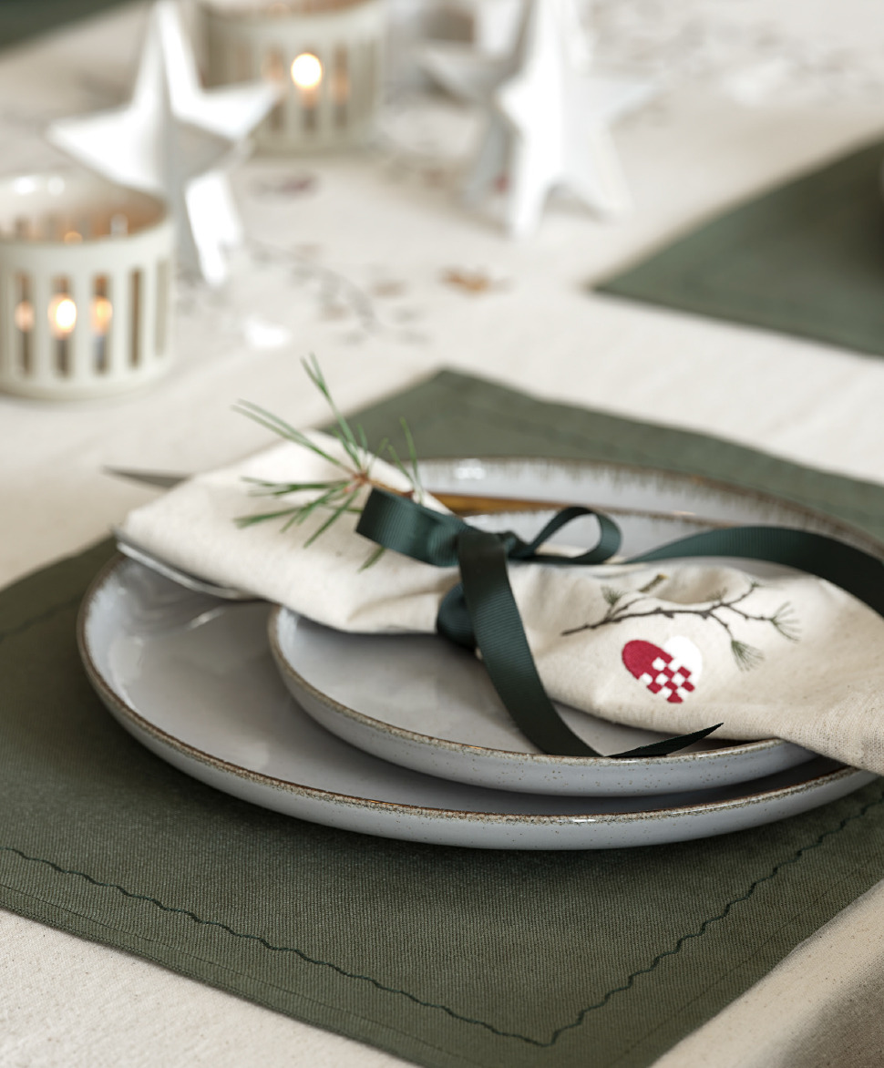 Stoffserviette NELLIKE mit Weihnachtsstickerei Fein säuberlich gefaltete Serviette auf einem Teller