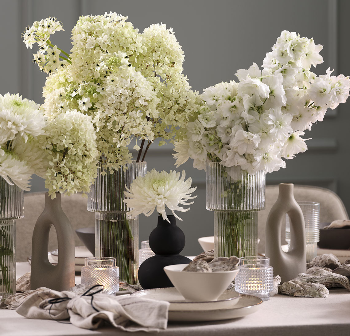 Schwarze Vase und Glasvasen mit Blumen auf einem Neujahrstisch