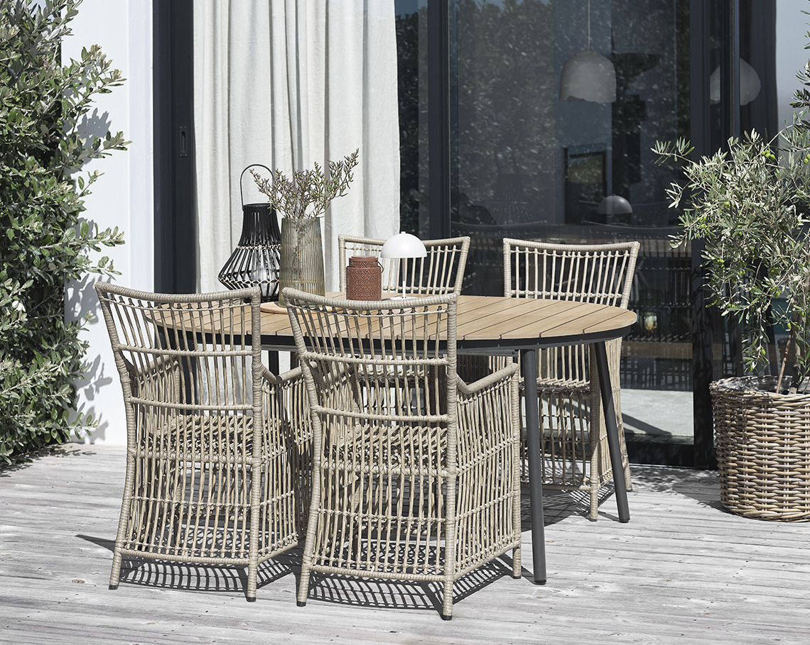 Ovaler Gartentisch mit vier Gartenstühlen auf einer Veranda