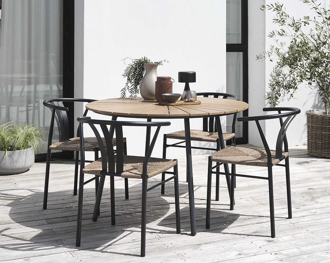 Runder Gartentisch mit vier Gartenstühlen auf einer Terrasse