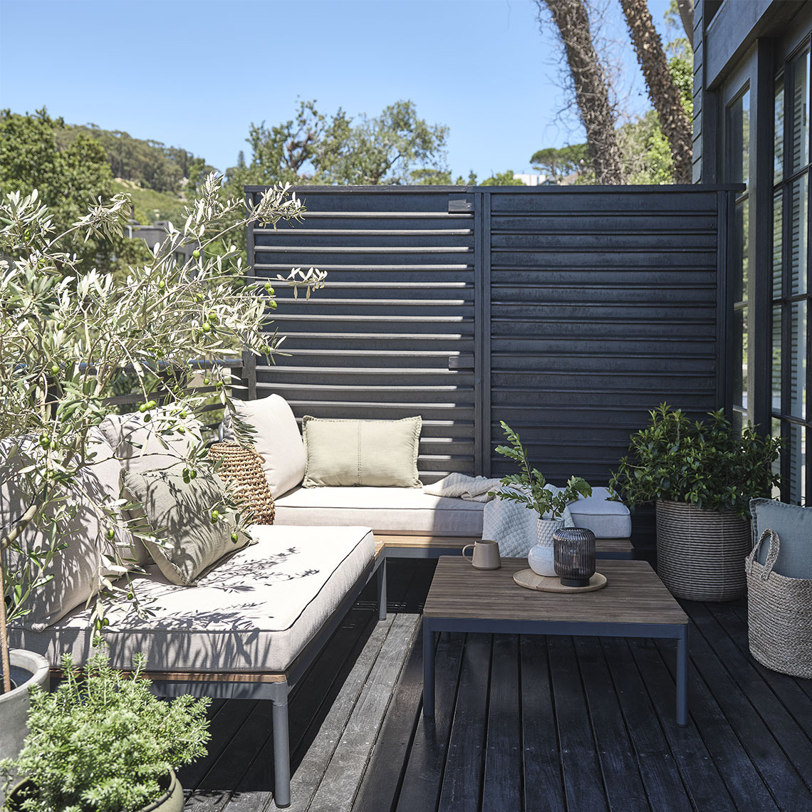 Lounge-Modul HOU aus Akazienholz Modulares Garten-Lounge-Set auf einer kleinen Terrasse mit Pflanzen und Pflanzgefäßen