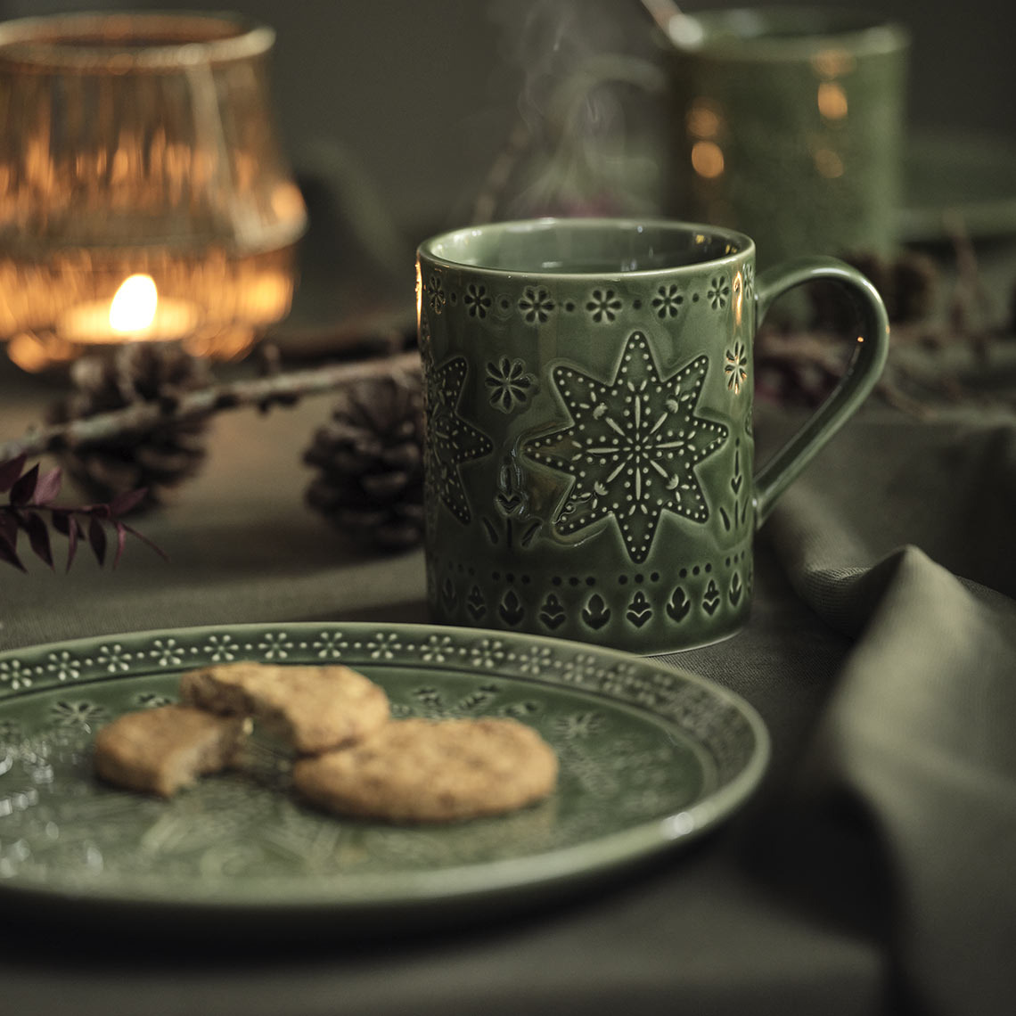 Grüner Weihnachtsteller und Becher auf einem Weihnachtstisch