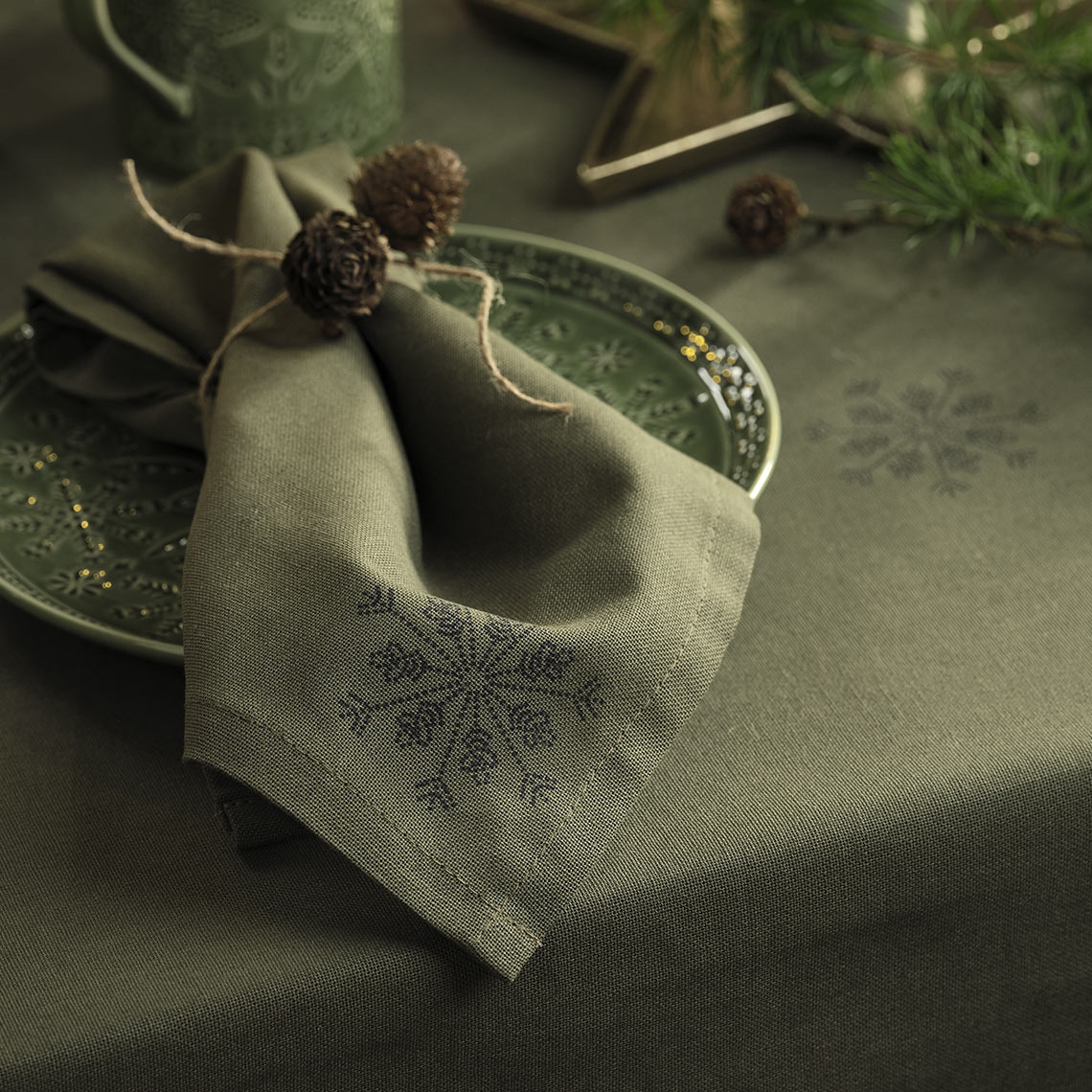 Grüne Weihnachtstischdecke und weihnachtliche Stoffserviette auf einem grünen Teller 