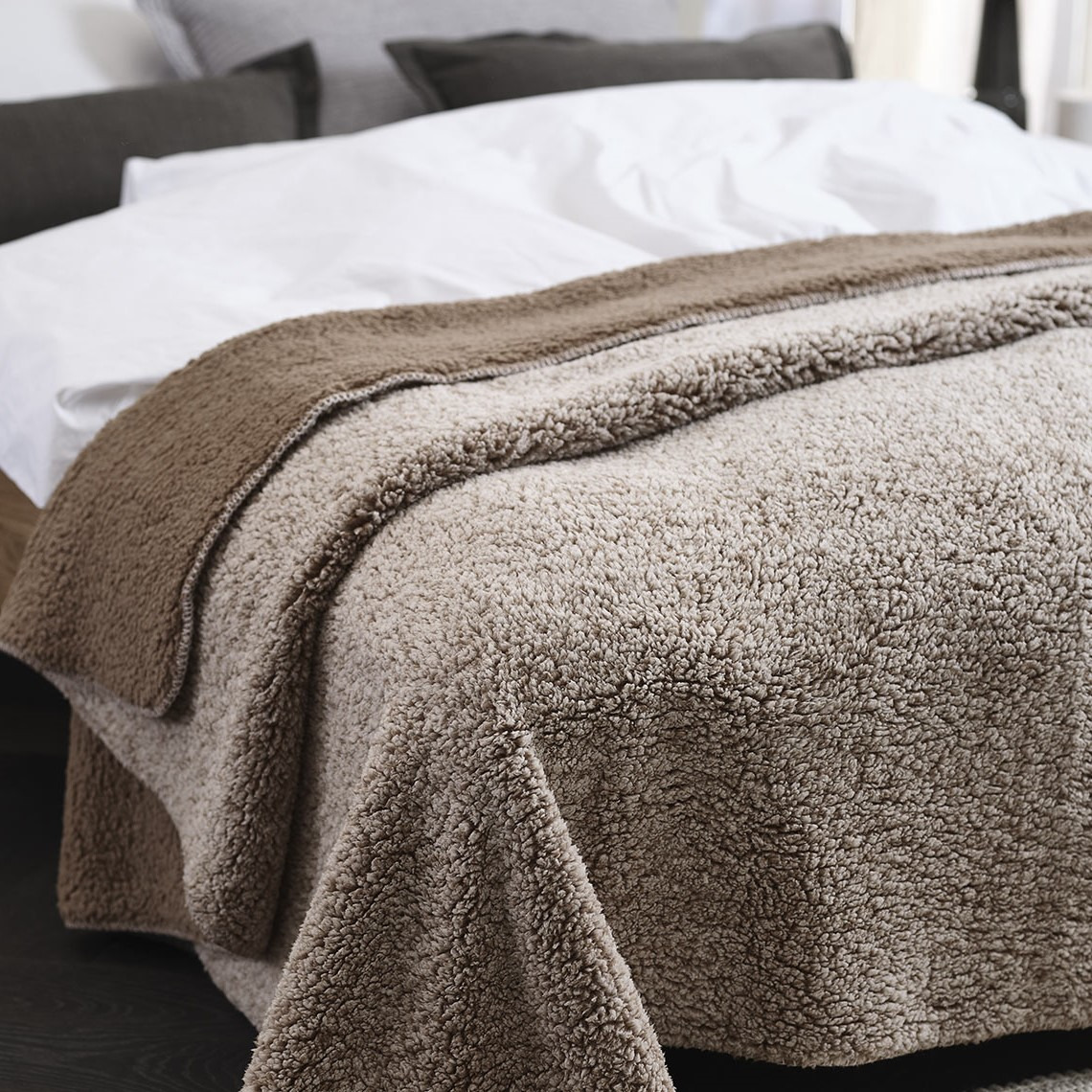 Kuschelige Fleecedecke STORFRYTLE Braune Fleecedecke auf einem Bett in einem Schlafzimmer