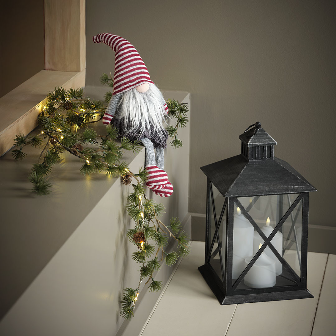 Wichtel SVADILFARI und Laterne PULKA Kleiner Wichtel mit über die Kante hängenden Beinen neben einer Laterne