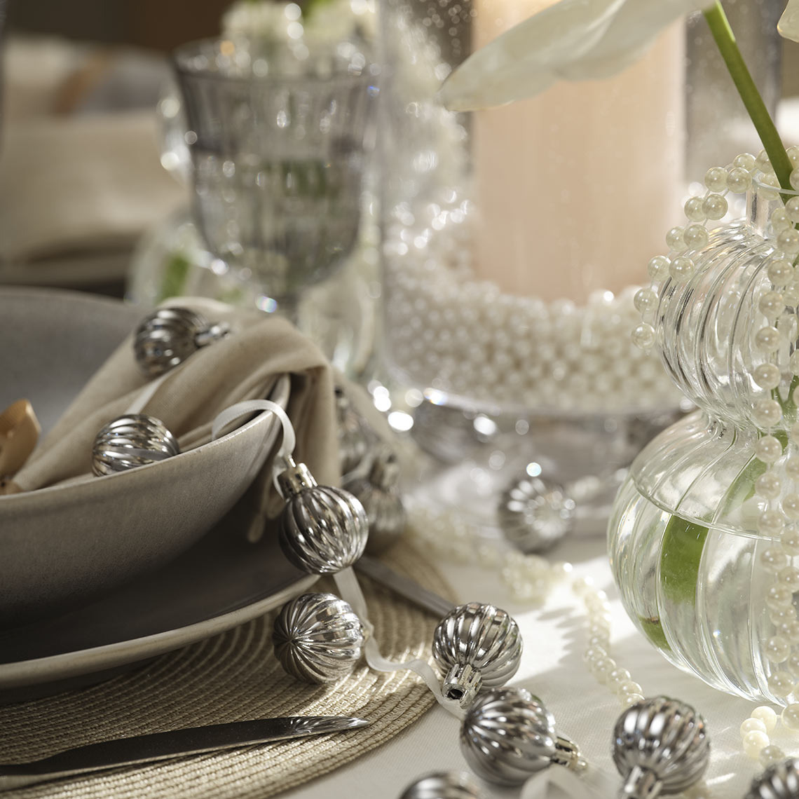 Weihnachtskugeln an einer Schnur auf einem Esstisch