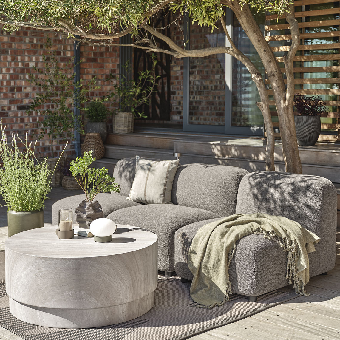 Lounge Modul in Grau als Sofa angeordnet und ein Loungetisch in Travertin-Optik