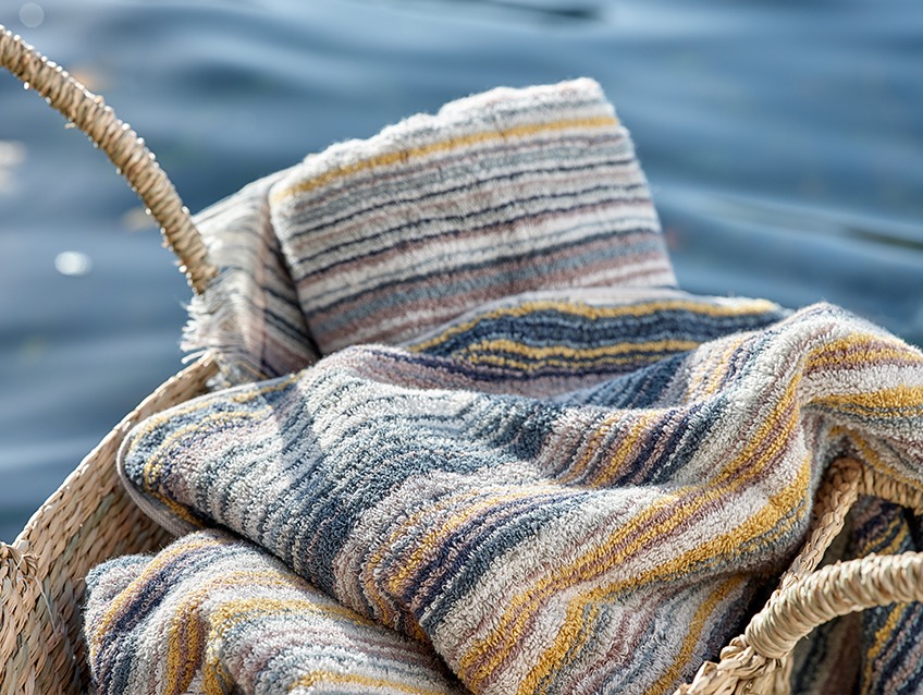 Weidenkorb mit gestreiften Handtüchern an einem See