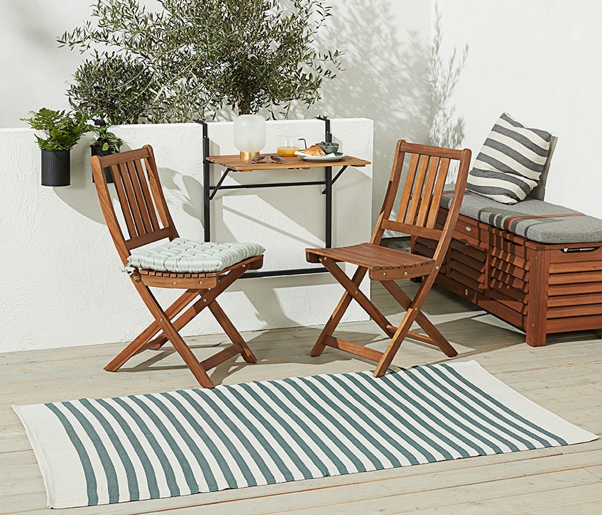 ELVESANGER-Teppich aus 100 % recyceltem Kunststoff Teppich aus recyceltem Kunststoff vor einem Bistro-Set auf einer Terrasse
