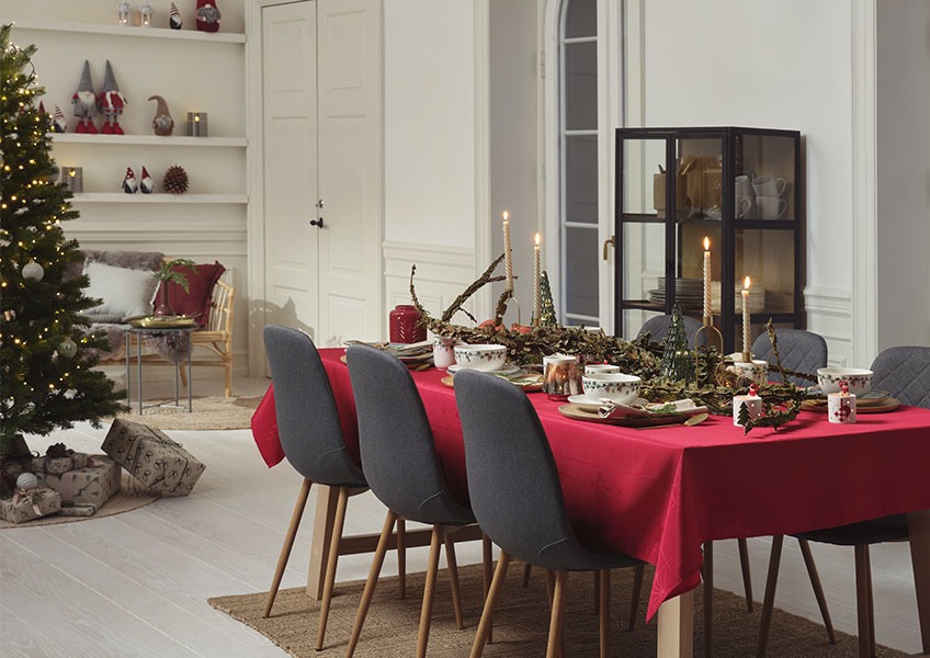 Weihnachtlich geschmückter Esstisch und Weihnachtsbaum mit Geschenken