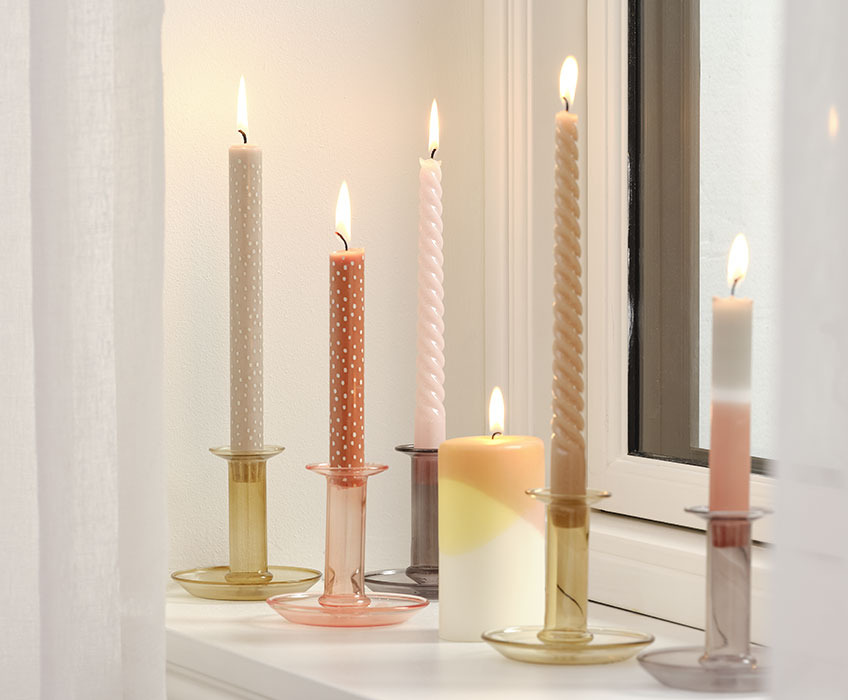 Kerzen in Kerzenhaltern auf einer Fensterbank 
