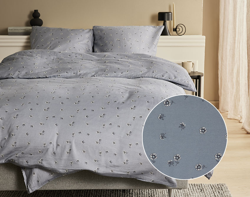Bett mit Satin-Bettwäsche mit kleinen Blumen auf dunkelgrauem Hintergrund 