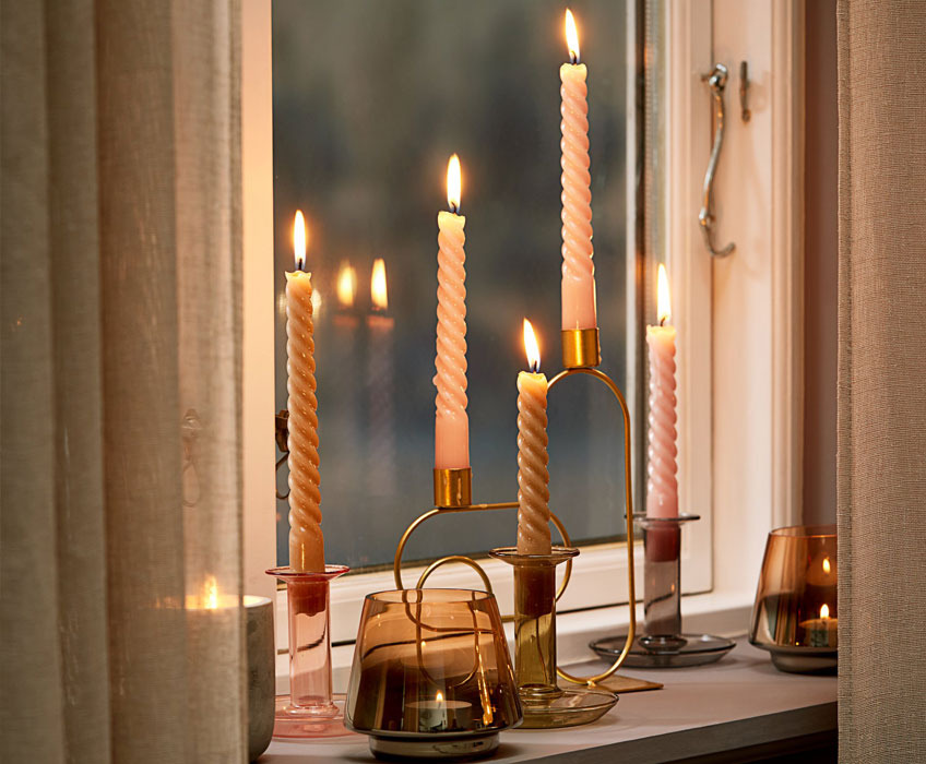 Kerzenhalter mit Kerzen in verschiedenen Designs auf einem Fensterbrett