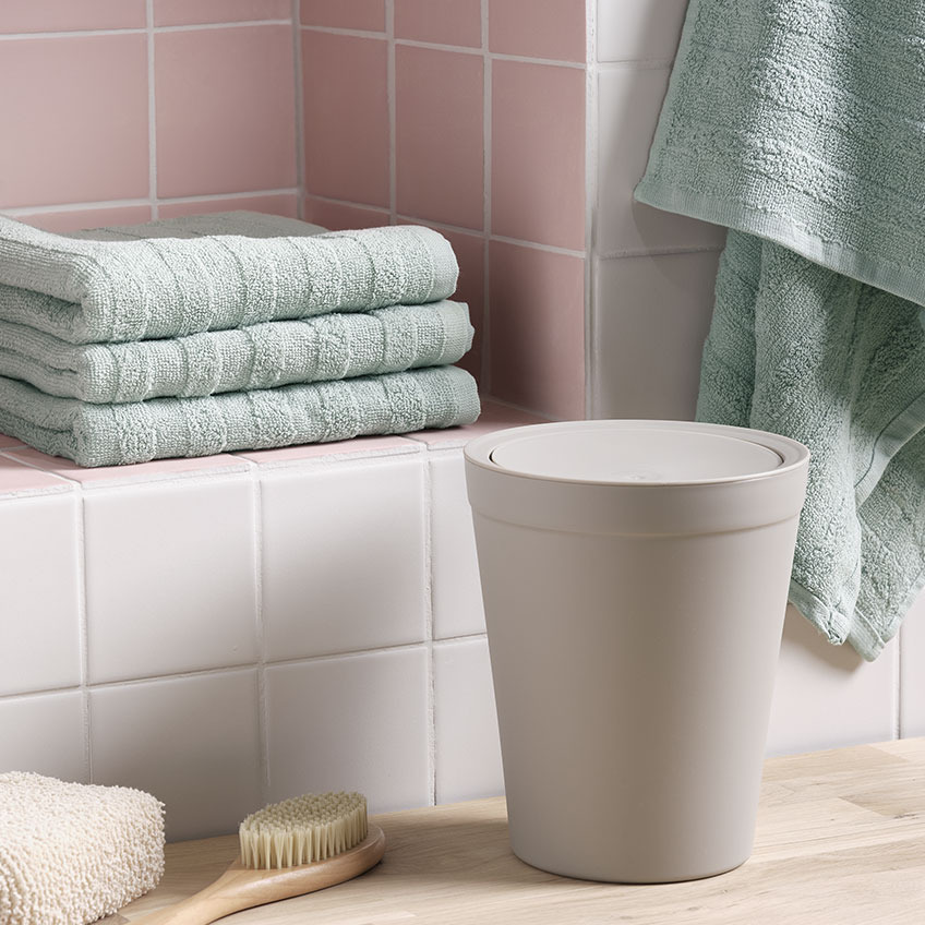Handtücher, Abfalleimer und eine Bürste in einem Badezimmer