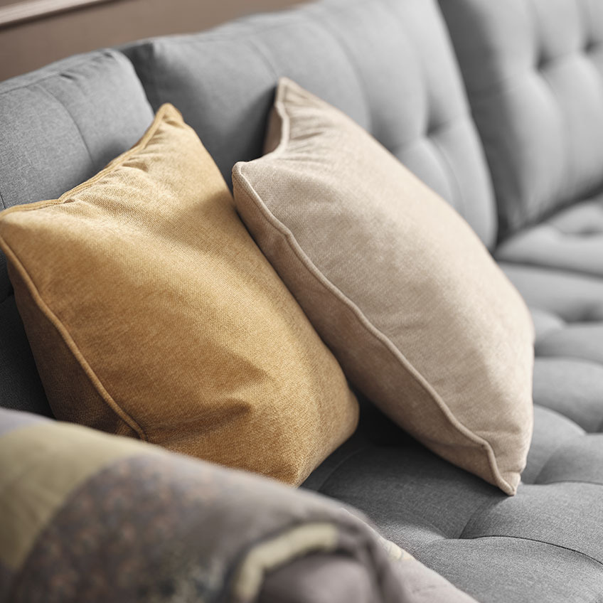Zierkissen HORNFIOL in Gelb und Beige Gelbes und beiges Zierkissen auf einem grauen Sofa