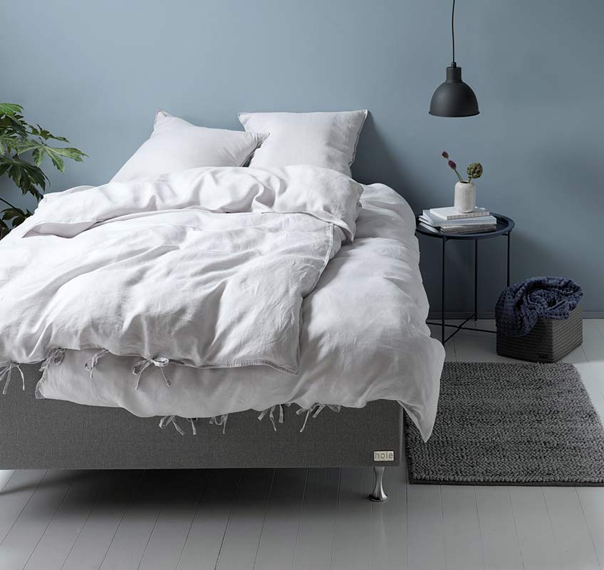 Leinenbettwäsche in Hellgrau auf einem grauen Bett
