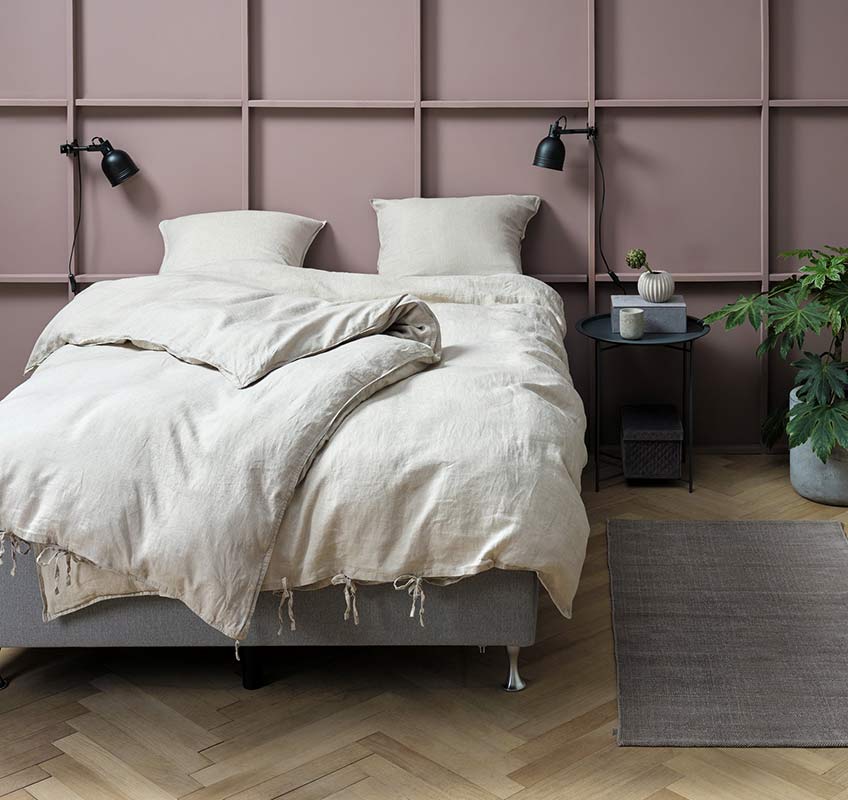 Leinenbettwäsche in Natur auf einem grauen Bett