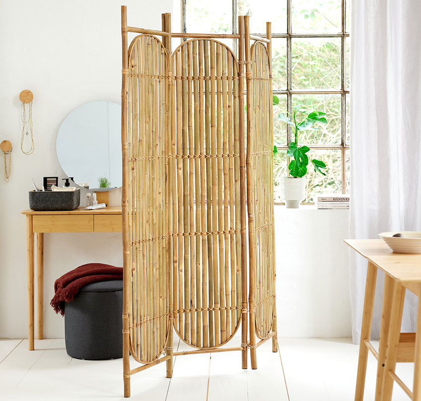 Paravent aus Bambus dient als Raumteiler zwischen einem Essbereich und einem Schlafbereich