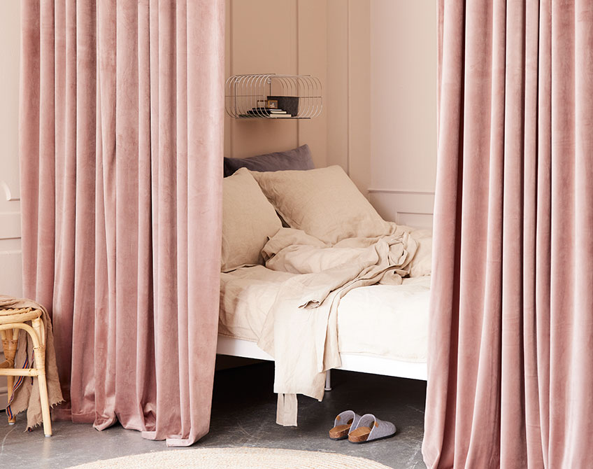 Rosafarbene Vorhänge, die einen Schlafbereich von einem großen Wohnzimmer trennen