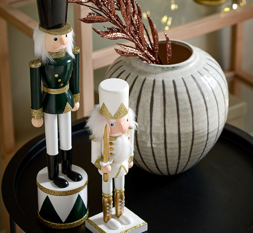 Zwei Weihnachtsfiguren und eine Vase auf einem schwarzen Beistelltisch