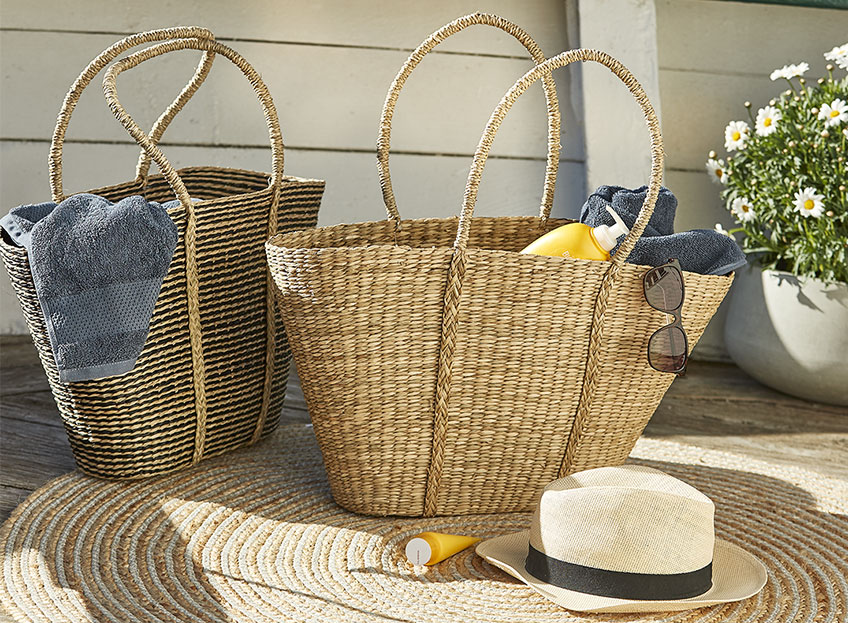 Zwei Strandtaschen aus Korbgeflecht mit Sonnencreme und Handtüchern