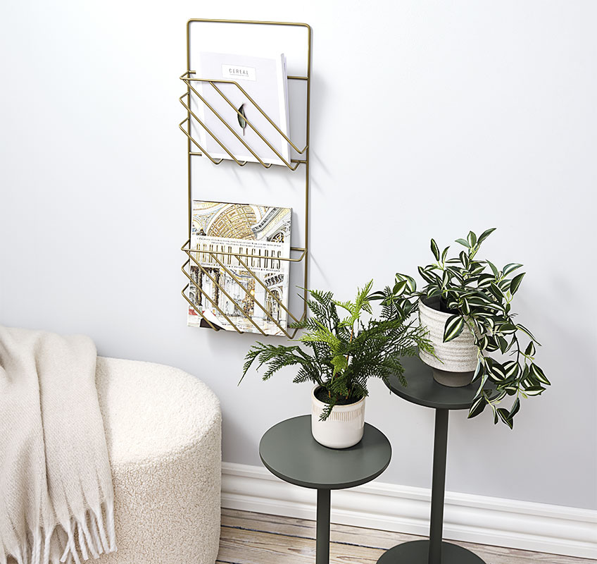 Zwei Blumenständer in olivgrün und ein goldener Zeitschriftenhalter, der an der Wand hängt. 