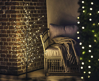 LED-Lichterbaum mit LED vor einer Hauswand und neben einem Outdoor-Sofa