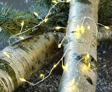 Leuchtende Lichterkette auf einem Baumstamm drapiert